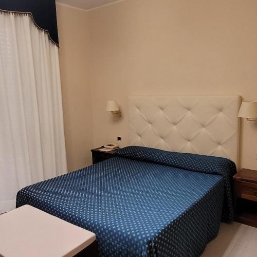 a hotel room with a bed with a blue comforter at Hotel Eden Sul Lago in Bolsena