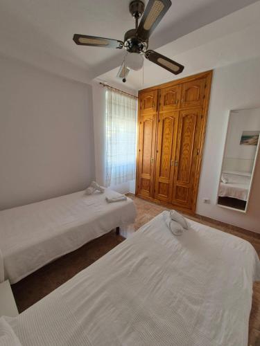 a bedroom with two beds and a ceiling fan at 3ºB Escobar in Nerja