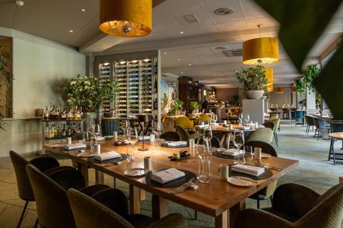 a restaurant with wooden tables and chairs and a bar at Parkhotel Tjaarda in Oranjewoud