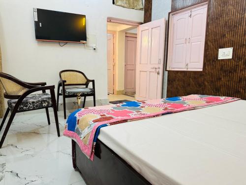 a bed in a room with two chairs and a tv at Kamaree-7BHK in Varanasi