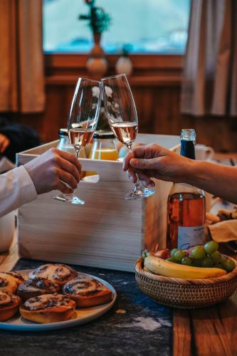 two people holding glasses of wine on a table with food at Naturhof eibl in Grossarl