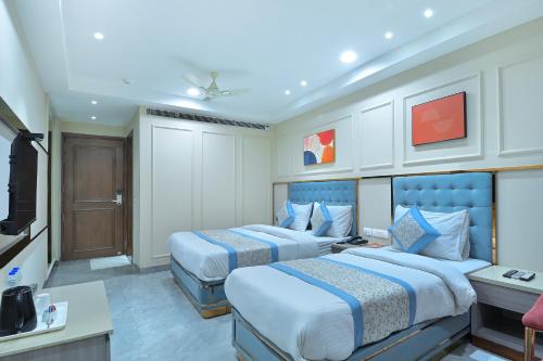 ニューデリーにあるHotel Sapphire House - 3 Mins Walk from Metro and 5 Mins from Rail Stationのベッド2台とテレビがあるホテルの部屋
