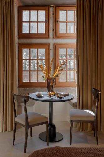 a dining room table with two chairs and a vase with flowers at MiHotel - Grenier à Sel de Pérouges in Pérouges