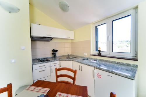 a kitchen with white cabinets and a table and a window at Apartments Ivan in Zadar