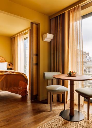a hotel room with a bed and a table and chairs at Le Jardin de Verre by Locke in Paris