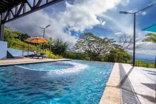 a swimming pool with an umbrella and a table at La Parada House in Heredia