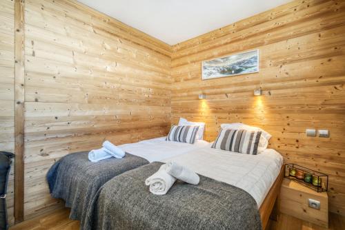 two beds in a room with wooden walls at Chalet Arktic - Catered Chalet - Sleeps 14 in Tignes