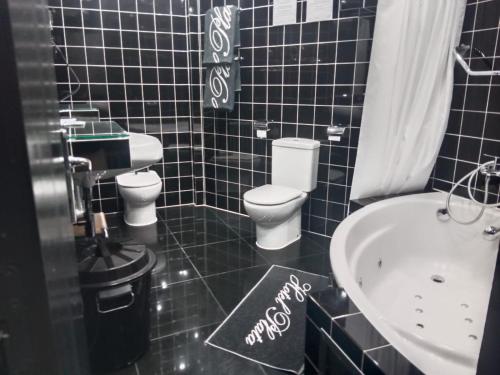 a black tiled bathroom with a toilet and a sink at Hotel Plata in Ibi