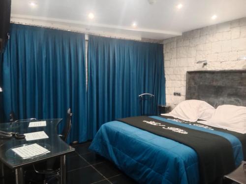 a bedroom with blue curtains and a bed with a desk at Hotel Plata in Ibi