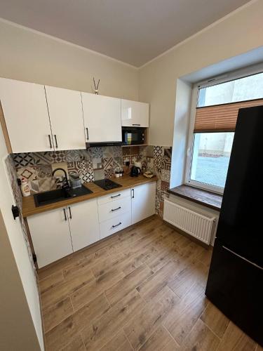 a kitchen with white cabinets and a sink and a window at Kamienica LOFT in Ciechocinek