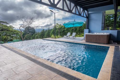 a swimming pool with two chairs and an umbrella at La Parada House in Heredia