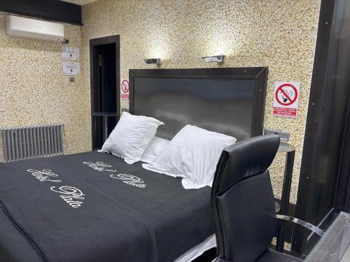 a black bed with white pillows and a black chair at Hotel Plata in Ibi