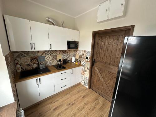 a kitchen with white cabinets and a black refrigerator at Kamienica LOFT in Ciechocinek