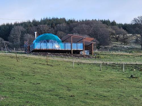 a blue tent in a field next to a field at Drum Farm Hideaways in Carron