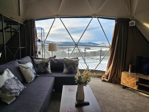 a living room with a couch and a large window at Drum Farm Hideaways in Carron