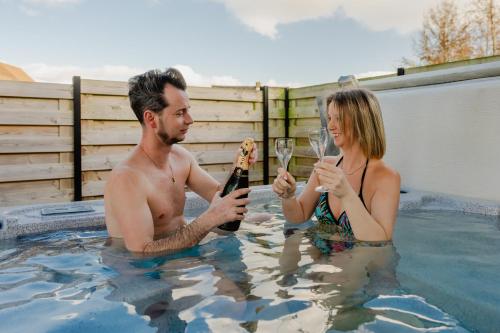 a man and woman holding glasses of wine in a swimming pool at Sauna Moments Villa in Torhout