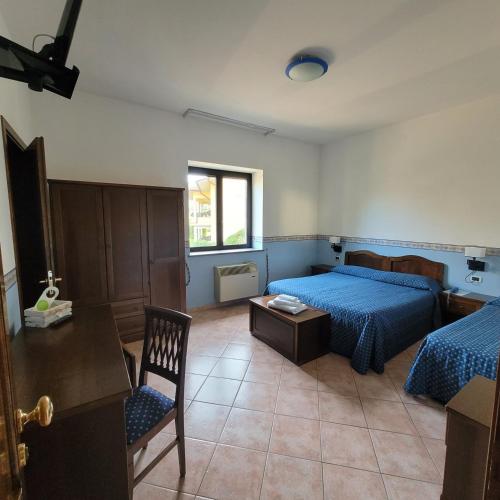 a bedroom with two beds and a table and a chair at Hotel Eden Sul Lago in Bolsena