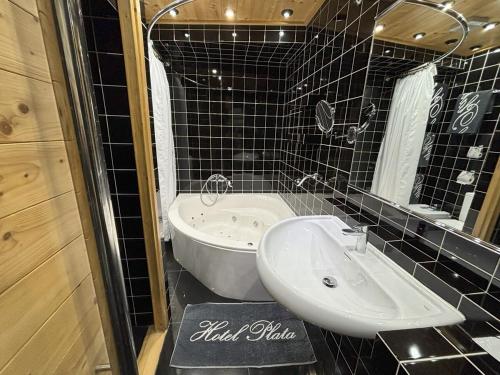 a black tiled bathroom with a sink and a tub at Hotel Plata in Ibi