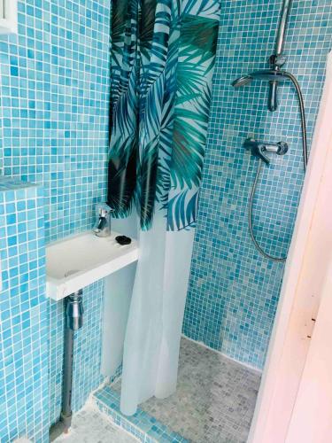 une salle de bain carrelée bleue avec un lavabo et une douche dans l'établissement SKY BUBBLE Bright Cosy Studio in Lyon, à Lyon