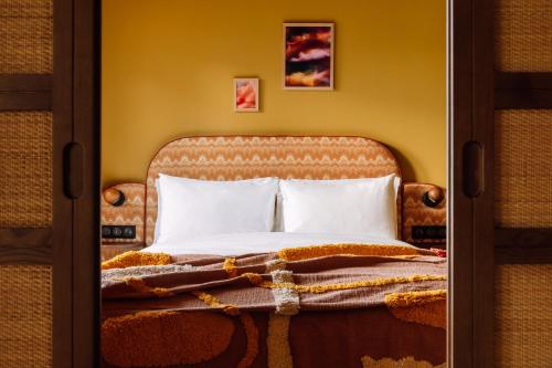 a bed with white pillows and a blanket at Le Jardin de Verre by Locke in Paris