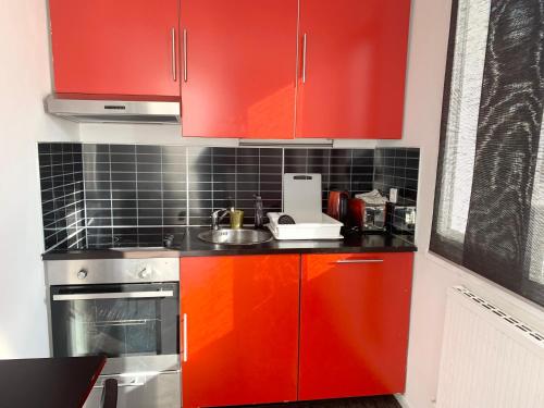 une cuisine avec des armoires rouges et un évier dans l'établissement Terrasse au pied de la gare, à Marseille