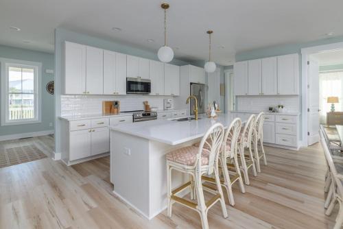 a kitchen with white cabinets and a kitchen island with chairs at New Build, walking distance to pool and beach! Perfect location on Harbor Island! in Cedar Reef Villas