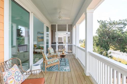 a screened porch with rocking chairs and a table at New Build, walking distance to pool and beach! Perfect location on Harbor Island! in Cedar Reef Villas
