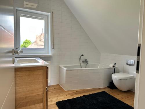 a bathroom with a tub and a sink and a window at Ferienhaus Wein & Wald mit Gartensauna in Landau in der Pfalz
