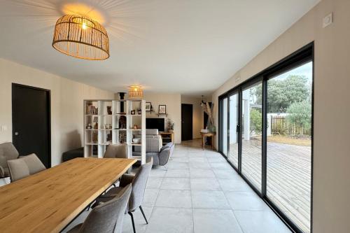 a dining room and living room with a table and chairs at La Villa Pinède avec SPA à 5 minutes de la mer in Brétignolles-sur-Mer
