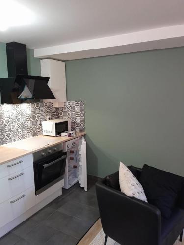 a living room with a couch and a kitchen at Le coucou, studio tout équipé proche gare in Saint-Brieuc