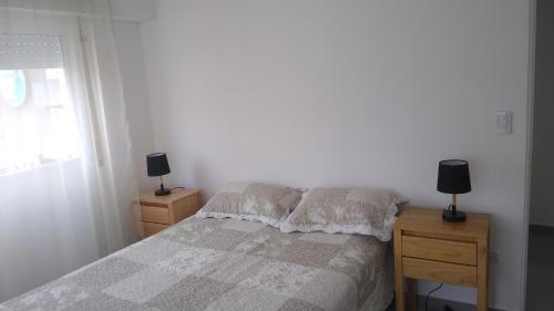 a bedroom with a bed and two night stands with lamps at Frente al mar in Pinamar