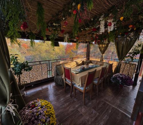 a dining room with a table and chairs and flowers at Къща за гости Дени in Chukovezer