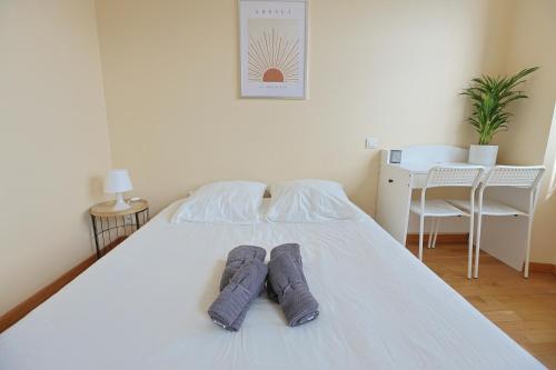 un lit blanc avec deux oreillers dessus dans l'établissement L'Instant Suny Centre-ville, à Saint-Étienne