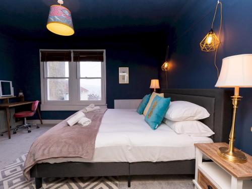 a bedroom with a large bed with blue walls at Spacious one bed house with parking - Pass the Keys in Bath