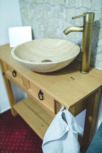 a bathroom sink with a wooden bowl on a wooden table at wellness Chata u Pinkasů in Písečná