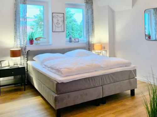 a bed in a bedroom with two windows at Neues Ferienhaus für Familien mit Garten und Sauna in Butjadingen