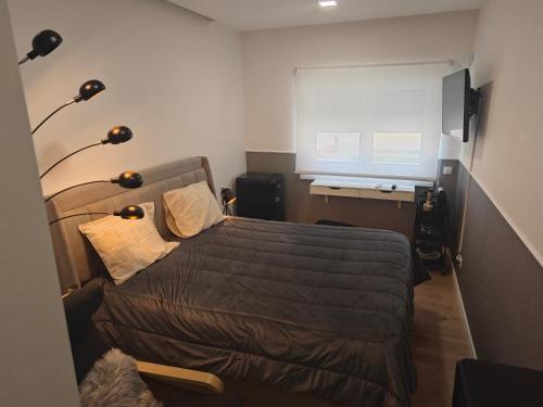 a bedroom with a bed and a desk and a window at Suítes Lua in Castelo Branco