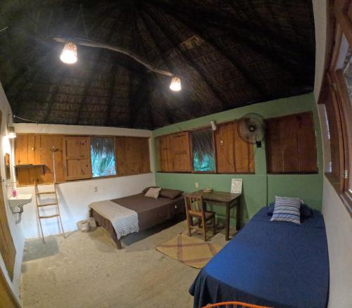 a bedroom with a bed and a table in a room at Cabañas La Escondida Mazunte in Mazunte