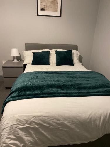 a bedroom with a large bed with a green blanket at 15 on Hill Crescent, 6 en-suite bedrooms, Sleeps 12 in Skegby