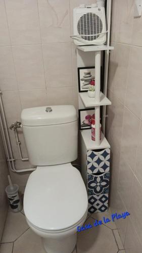 La salle de bains est pourvue de toilettes blanches et d'un ventilateur. dans l'établissement Casa de la Playa,Mer 100m, parking,animaux,clim,wifi, au Barcarès
