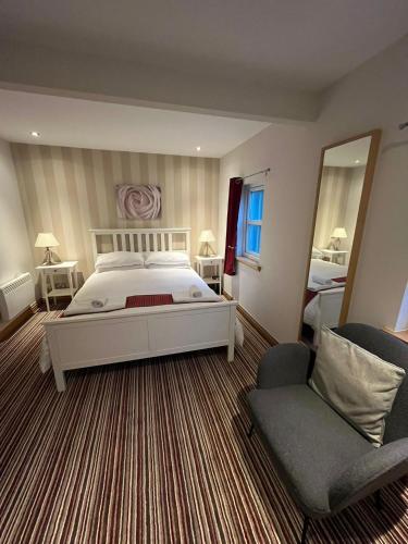 a bedroom with a bed and a chair and a mirror at River Cottage Hot tub spa in Drumnadrochit