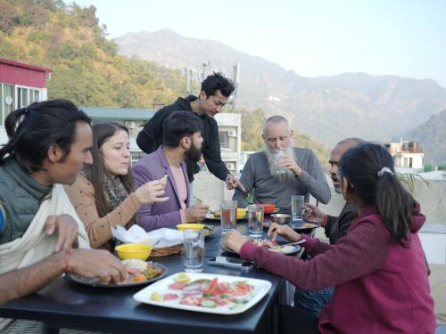 a group of people sitting around a table eating food at Skyard Premium, Tapovan in Rishīkesh