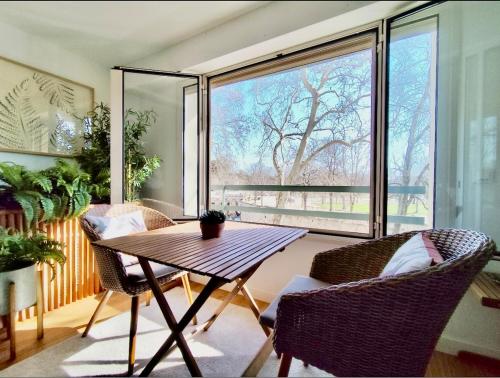 une pièce avec une table et des chaises et une grande fenêtre dans l'établissement Le Dandy de la Fontaine climatisation et garage, à Nîmes