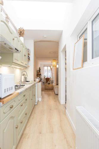 a kitchen with white cabinets and a hard wood floor at Maison avec jardin à Lille - La Pépinière in Lille