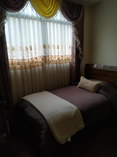 a bed in a bedroom with a window with curtains at Hostal Terrabella SRL in La Paz