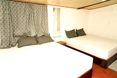two beds in a small room with a window at Lands End in Madikeri