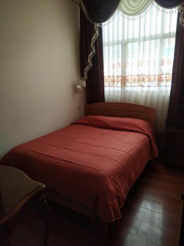 a bedroom with a red bed with a window at Hostal Terrabella SRL in La Paz