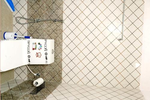 a white tiled bathroom with a toilet paper dispenser at Lands End in Madikeri