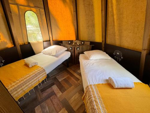 two beds in a small room with yellow walls at Whaka Lodge in Seissan