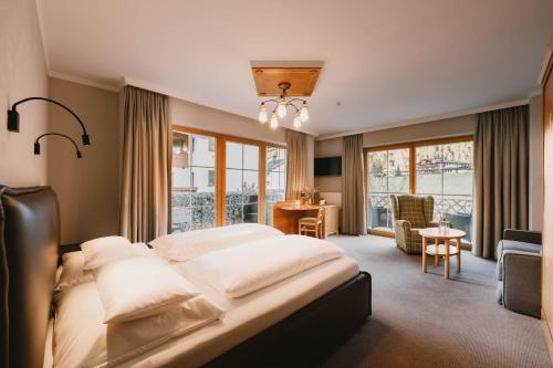 a hotel room with a large bed and a desk at Familotel Kindl in Neustift im Stubaital